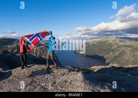 Pathway Preikestolen (Pulpit Rock). Couple avec le drapeau de la Norvège. Panorama du Lysefjord. Ensoleillé dans les montagnes Banque D'Images