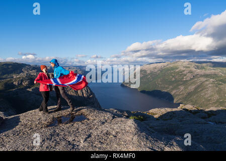 Preikestolen, voie de la Norvège. Couple aimant avec le drapeau de la Norvège. Panorama du Lysefjord Banque D'Images