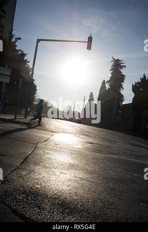 l'homme français adulte traverse la traversée de zébra seul dans la rue vide contre-jour par le soleil Banque D'Images