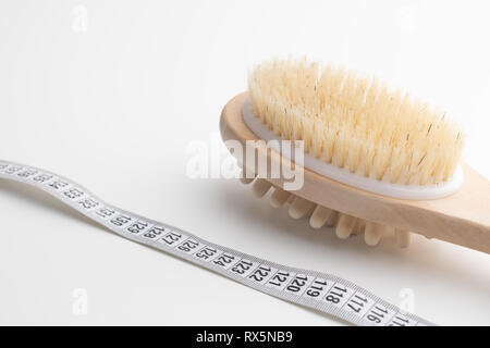 Brosse de massage à sec avec ruban de mesure sur blanc 24. Santé et alimentation. Concept de remise en forme. Banque D'Images