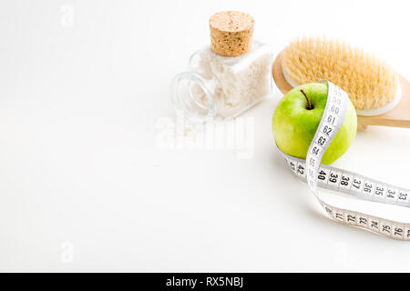 Brosse de massage à sec avec ruban de mesure. Seule la pomme verte et le flacon en verre avec sel de mer sur blanc 24. Banque D'Images