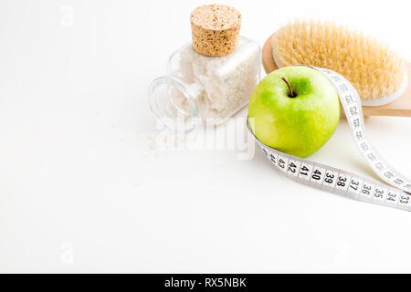 Brosse de massage à sec avec ruban de mesure. Seule la pomme verte et le flacon en verre avec sel de mer sur blanc 24. Banque D'Images