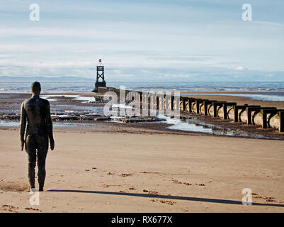 L'un des hommes de fer d'Antony Gormley debout dans un autre endroit sur Crosby Beach Banque D'Images