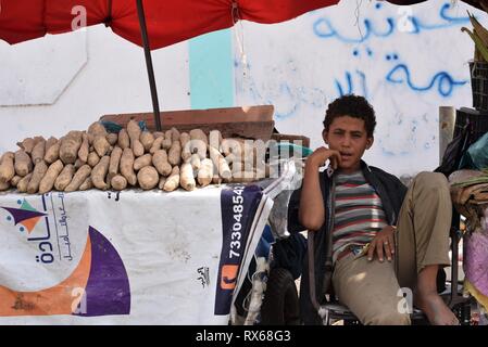 D'Aden, au Yémen. Mar 8, 2019. Un enfant est assis à côté d'un stand du vendeur dans une rue d'Aden, au Yémen, le 8 mars 2019. Des milliers de jeunes Yéménites ont été poussées dans les rues à la suite d'un conflit militaire croissante qui a éclaté entre les forces du gouvernement du Yémen et les rebelles Houthi en 2015. Le nombre d'enfants des rues continue d'augmenter sur une base quotidienne que les combats se poursuivent, l'expansion pour inclure un plus grand nombre de provinces dans le pays arabe au milieu de l'absence de solutions politiques à la fin de quatre ans de guerre civile. Credit : Murad Abdo/Xinhua/Alamy Live News Banque D'Images