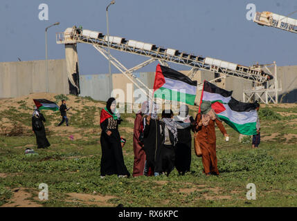 8 mars 2019 - Gaza, Palestine, 8 mars 2019. Des manifestants palestiniens brûlent des pneus et des vagues le drapeau palestinien, avec quelques pierres de hurling vers la clôture, dans la région de Malika à l'est de la bande de Gaza. Des manifestants palestiniens s'étaient rassemblés à différents endroits le long de la frontière au cours de cette Gaza-Israeli vendredi 50e Grande Marche du retour rallye, et selon le ministère de la santé dans la bande de Gaza cinq Palestiniens ont été blessés dans ce Vendredi, Mars 1 dans un état critique. Selon l'armée israélienne, des ballons incendiaires chargé d'explosifs ont été libérés de la bande de Gaza vers le sud d'Israël. Banque D'Images