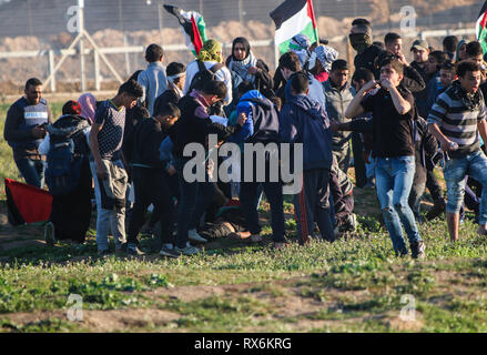 8 mars 2019 - Gaza, Palestine, 8 mars 2019. Des manifestants palestiniens brûlent des pneus et des vagues le drapeau palestinien, avec quelques pierres de hurling vers la clôture, dans la région de Malika à l'est de la bande de Gaza. Des manifestants palestiniens s'étaient rassemblés à différents endroits le long de la frontière au cours de cette Gaza-Israeli vendredi 50e Grande Marche du retour rallye, et selon le ministère de la santé dans la bande de Gaza cinq Palestiniens ont été blessés dans ce Vendredi, Mars 1 dans un état critique. Selon l'armée israélienne, des ballons incendiaires chargé d'explosifs ont été libérés de la bande de Gaza vers le sud d'Israël. Banque D'Images