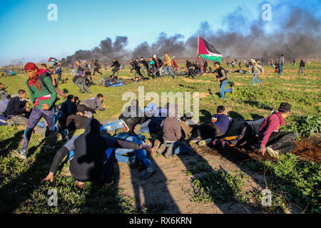 8 mars 2019 - Gaza, Palestine, 8 mars 2019. Des manifestants palestiniens brûlent des pneus et des vagues le drapeau palestinien, avec quelques pierres de hurling vers la clôture, dans la région de Malika à l'est de la bande de Gaza. Des manifestants palestiniens s'étaient rassemblés à différents endroits le long de la frontière au cours de cette Gaza-Israeli vendredi 50e Grande Marche du retour rallye, et selon le ministère de la santé dans la bande de Gaza cinq Palestiniens ont été blessés dans ce Vendredi, Mars 1 dans un état critique. Selon l'armée israélienne, des ballons incendiaires chargé d'explosifs ont été libérés de la bande de Gaza vers le sud d'Israël. Banque D'Images