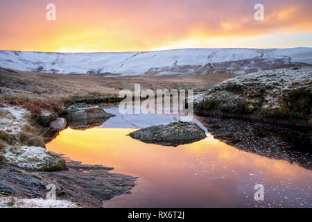 Pont AR, Elan Elan valley, le Pays de Galles. Scène enneigée d'Afon elan qui coule vers craig goch sur orange lever du soleil avec la réflexion du ciel Banque D'Images