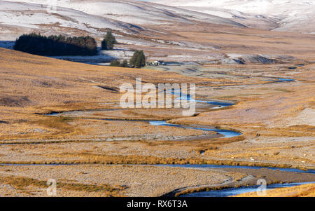 Pont AR, Elan Elan valley, le Pays de Galles. Scène enneigée d'Afon elan river serpente à travers le paysage de montagne avec bâtiment de ferme dans la distance Banque D'Images