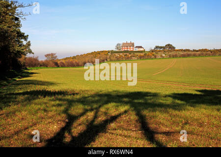 Une vue sur les terres agricoles à partir d'un sentier public vers une maison sur une colline sur Blakeney Downs, Norfolk, Angleterre, Royaume-Uni, Europe. Banque D'Images