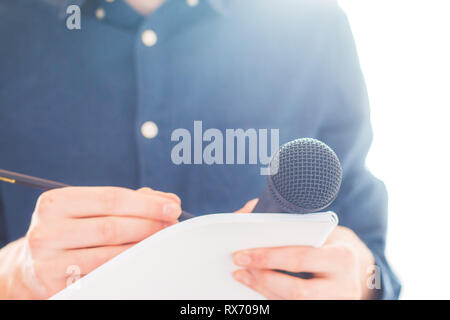 Cut-out d'un journaliste mâle dans un maillot bleu lors d'une conférence de presse qui est la prise de notes et la tenue d'un microphone Banque D'Images