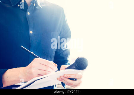 Cut-out d'un journaliste mâle dans un maillot bleu lors d'une conférence de presse qui est la prise de notes et la tenue d'un microphone Banque D'Images