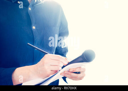 Cut-out d'un journaliste mâle dans un maillot bleu lors d'une conférence de presse qui est la prise de notes et la tenue d'un microphone Banque D'Images