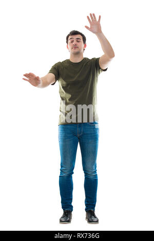 Portrait jeune homme occasionnels recherchant à mains tendues et les yeux fermés comme des aveugles marchant dans l'obscurité isolated over white background Banque D'Images