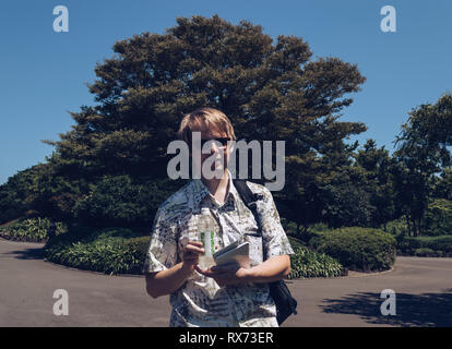 Dans l'homme chemise rétro avec sac à dos dans une bouteille de plastique holding parc Banque D'Images