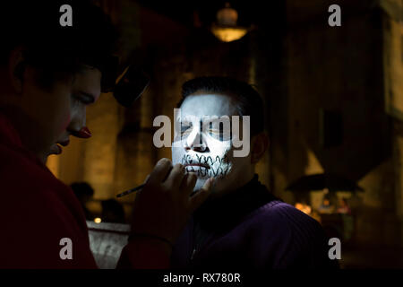 Maquilleuse peint un jeune visage de l'homme comme un squelette. Banque D'Images