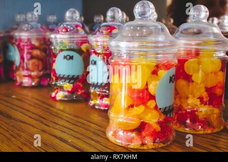 Bonbons colorés dans des pots en plastique sur une étagère dans un sweet shop Banque D'Images