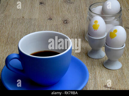 Grande tasse de café et des œufs de pâques avec le poulet peint sur eux et les oeufs dans un bocal de verre sur fond de bois Banque D'Images