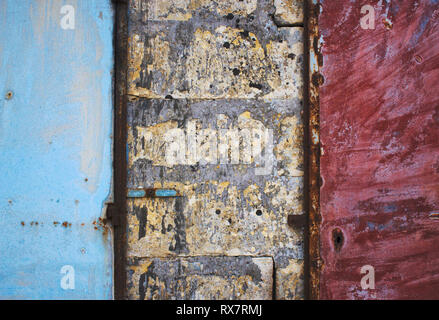 En métal peint bleu et rouge portes dans un mur de béton et de brique formant un abstract grunge texture background Banque D'Images