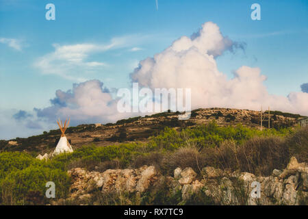 Toile Blanche (tipi ou wigwam) campé dans un champ sous un ciel nuageux ciel bleu Banque D'Images