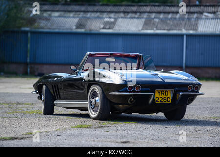 1966 Chevrolet Corvette Stingray cabriolet garé à côté d'un vieux bâtiment de travaux publics Banque D'Images