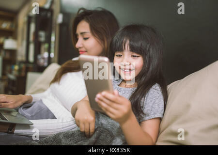 Mère et fille à l'aide d'un ordinateur portable et smartphone ensemble dans une chambre. technologie concept Banque D'Images