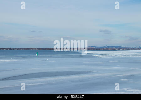 La bouée verte sur le fleuve Saint-Laurent en hiver - vue de Montréal en arrière-plan. Des couleurs douces Banque D'Images