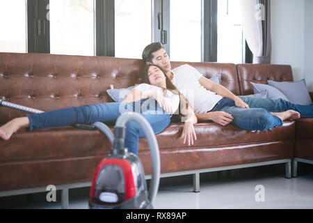 Man mari nettoyer la maison aider femme et femme de ménage prendre une sieste sur canapé après le nettoyage de l'ensemble de la salle assez couple ensemble Banque D'Images