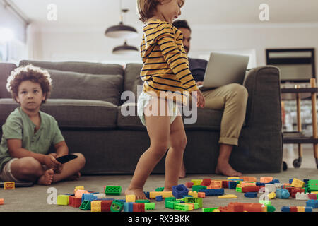 L'homme à la une fois que les enfants et le travail à domicile. Petit enfant devant ses composantes situées partout sur le sol. Banque D'Images