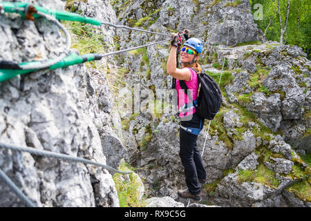 Jeune fille heureuse traversée d'une via ferrata pont de fil à Baia de Fier, la Roumanie. Sur un pont indien klettersteig avec une joyeuse, femme aventureux steppin Banque D'Images