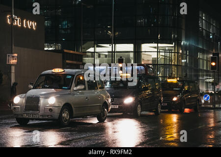Londres, Royaume-Uni - 26 janvier 2019 : Des taxis attendent les clients sur une route dans le Canary Wharf sur une soirée d'hiver pluvieux. Canary Wharf est un quartier financier animé Banque D'Images