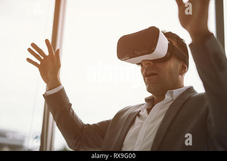 Excited businessman en rv headset sitting in office Banque D'Images
