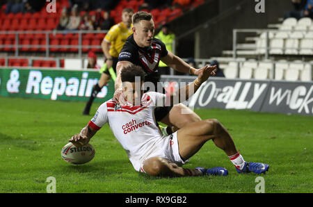 St Helens Saints' Regan Grace va au-dessus pour un essai passé London Broncos' Matty Fleming, au cours de la Super League Betfred match au stade totalement méchants, St Helens. Banque D'Images