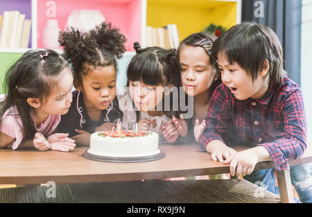 Groupe d'enfants bénéficiant d'un souffle d'anniversaire la bougie on cake Banque D'Images