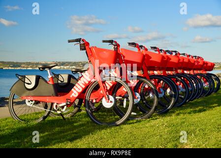 L'uber Jump le covoiturage (vélo partager) rouge, des vélos électriques (e-bikes) alignés sur l'herbe sur Harbour Island, San Diego, USA Banque D'Images