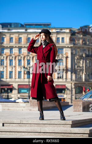 Portrait complet du corps. Belle jeune femme brune en élégant dans un long manteau bourgogne walking in spring street Banque D'Images