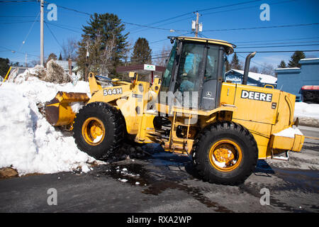 Un John Deere 544H la chargeuse sur roues le mouvement de la neige d'une entrée en spéculateur, NY USA Banque D'Images