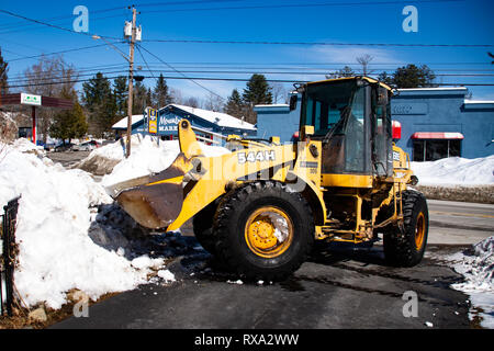 Un John Deere 544H la chargeuse sur roues le mouvement de la neige d'une entrée en spéculateur, NY USA Banque D'Images