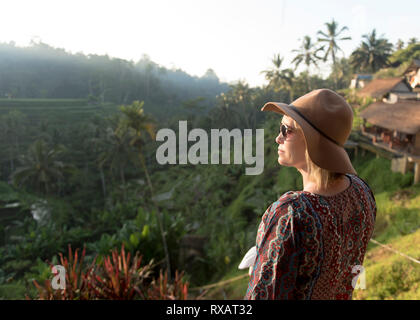 Vue latérale d'une femme portant des lunettes de soleil à la vue à la montagne en se tenant sur le contre ciel clair Banque D'Images