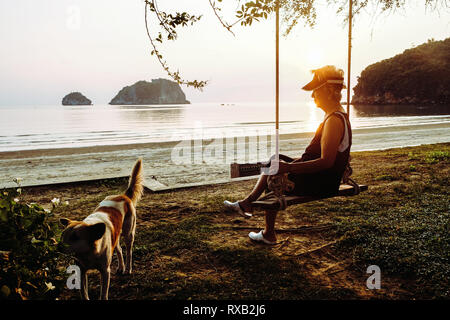 Senior woman relaxing sur les balançoires avec son chien Banque D'Images