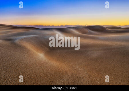 La lumière du soleil du matin le lever du soleil sur les dunes de sable intactes sans vie dans la zone déserte de Stockton Beach en Australie - partie à distance de parc national avec la pluie Banque D'Images