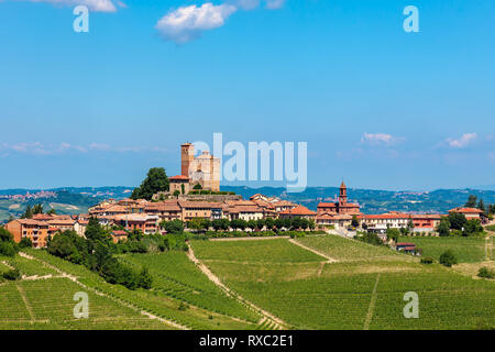 Petite cité médiévale sur la colline avec twn vignes vertes sous ciel bleu en Piémont, Italie du Nord. Banque D'Images