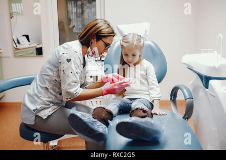 Jolie petite fille assise dans le bureau du dentiste Banque D'Images