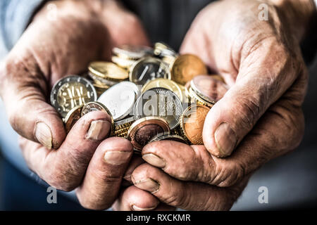 Pensionné homme tenant en mains les pièces en euros. Thème de faibles pensions. Banque D'Images