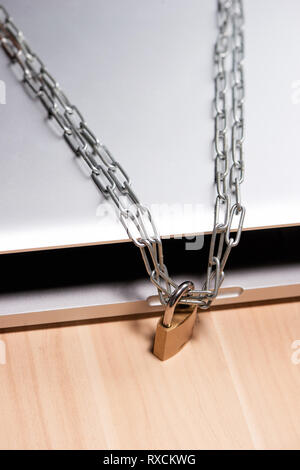 La chaîne lourde avec un cadenas autour d'un ordinateur portable sur la table. Banque D'Images