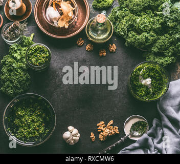 Kale recettes Information sur les aliments frais avec fond feuilles de chou et les ingrédients pour le pesto sur noir table de cuisine, vue de dessus du châssis, Banque D'Images