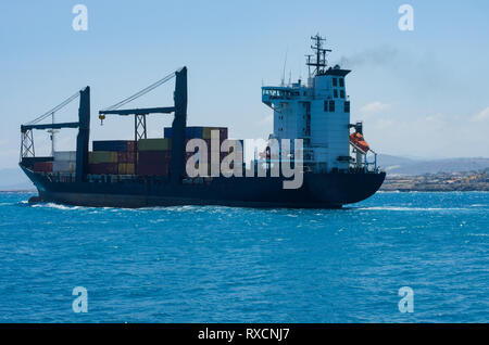 Container Ship sails hors de la Baie d'Héraklion dans la mer ouverte en arrière-plan les montagnes et le port Banque D'Images