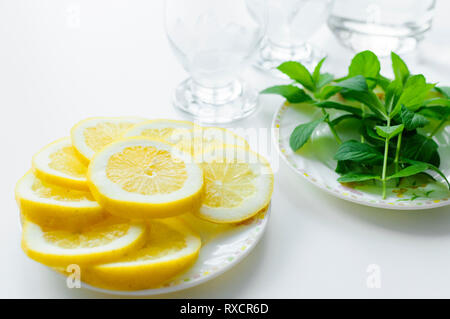 Été mis en place à partir de la préparation une boisson rafraîchissante avec des feuilles de menthe fraîche et rondelles de citron juteux avec deux verres dans l'arrière-plan. Banque D'Images