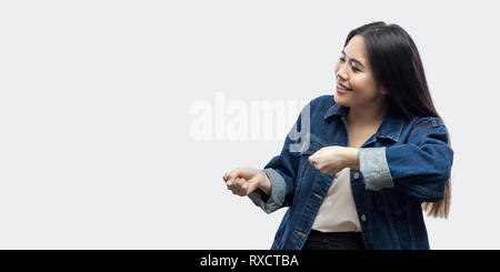 Portrait de profil Vue de côté drôle belle brune asian young woman in casual veste bleue avec un miroir debout et essayer de tirer geste montrant Banque D'Images
