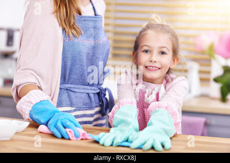 Petite fille et sa maman dans la cuisine nettoyage des tabliers Banque D'Images